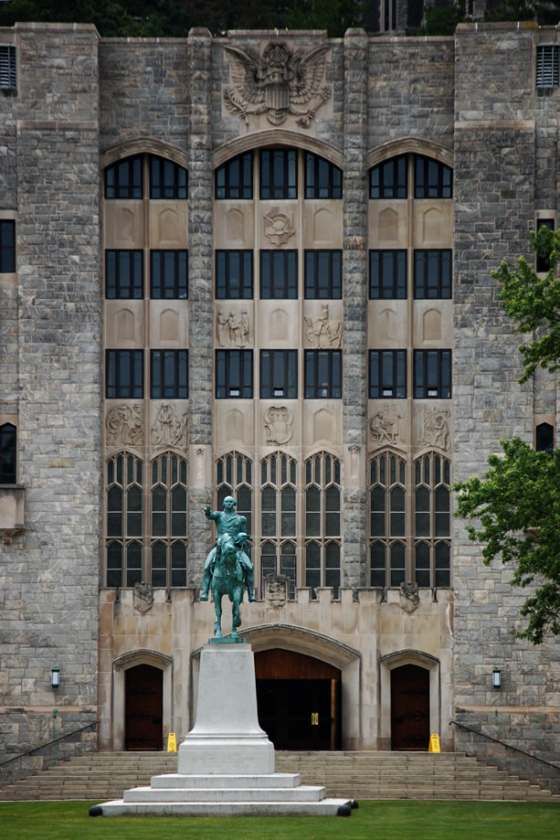 A statue of a man on horseback in front of an old building.